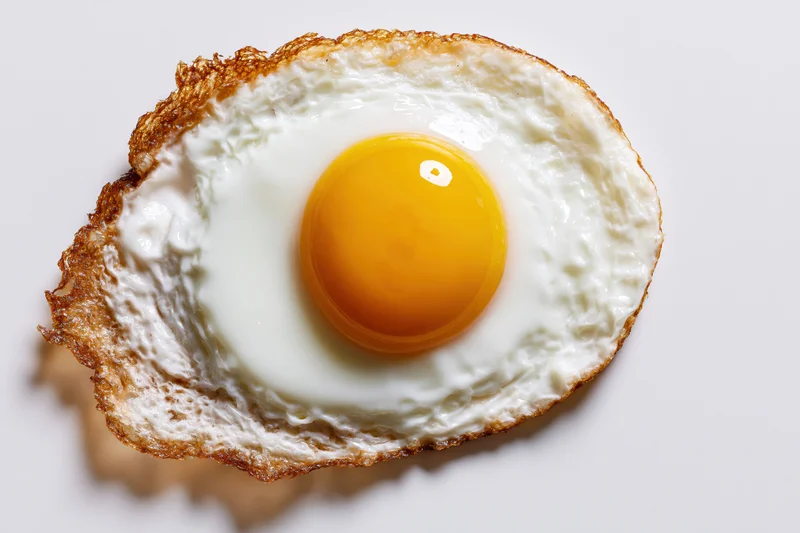 Single fried egg viewed from directly above on a white surface