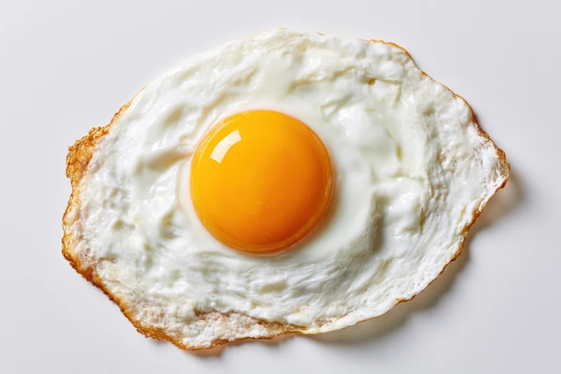 Single fried egg sunny-side up with intact yolk centered on white surface