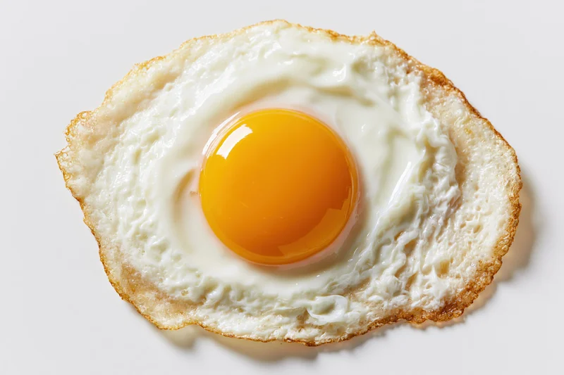 Single fried egg sunny-side up with intact yolk centered on white surface