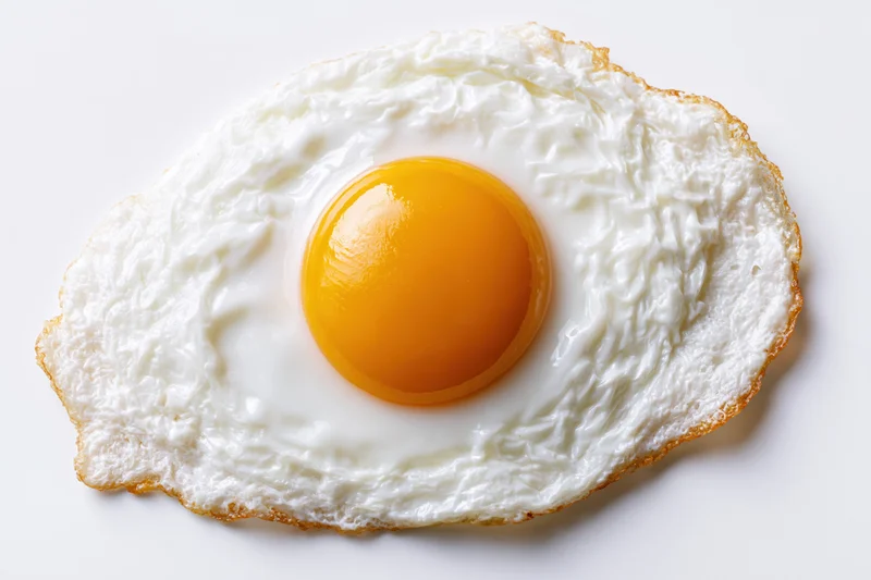 Single fried egg sunny-side up with intact yolk centered on white surface