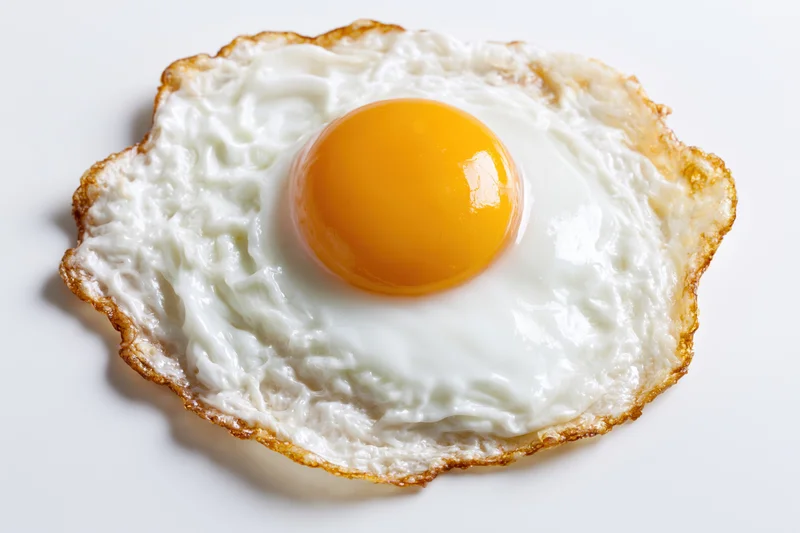 Single fried egg sunny side up on a white surface