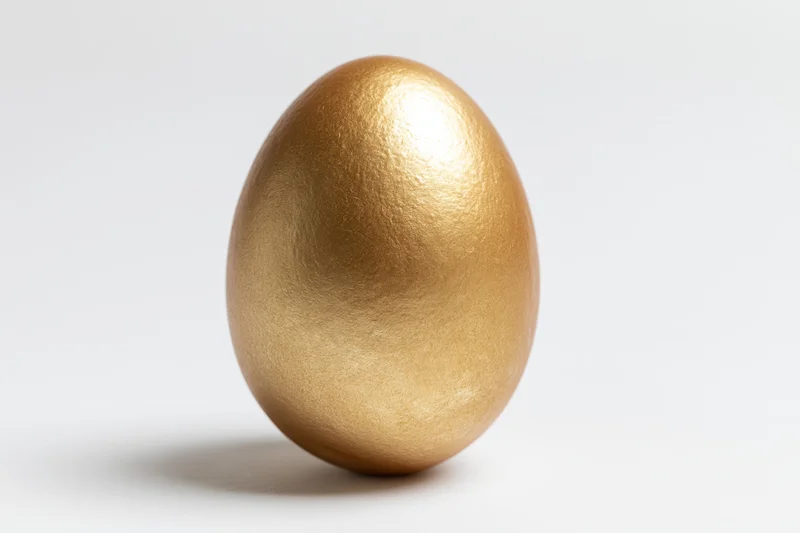 Golden painted egg standing upright centered against white background