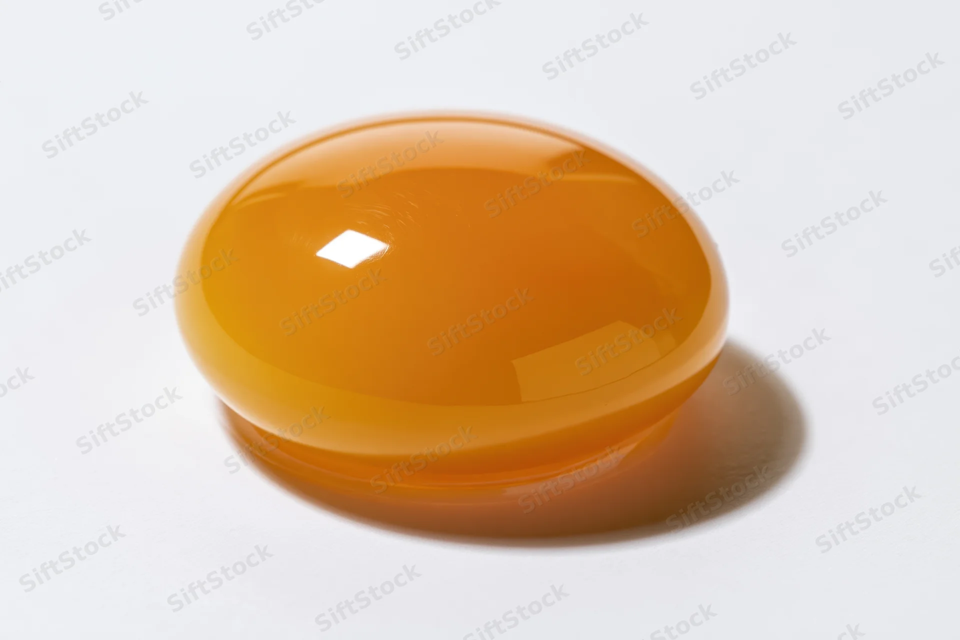A single raw egg yolk sitting intact on a pure white surface
