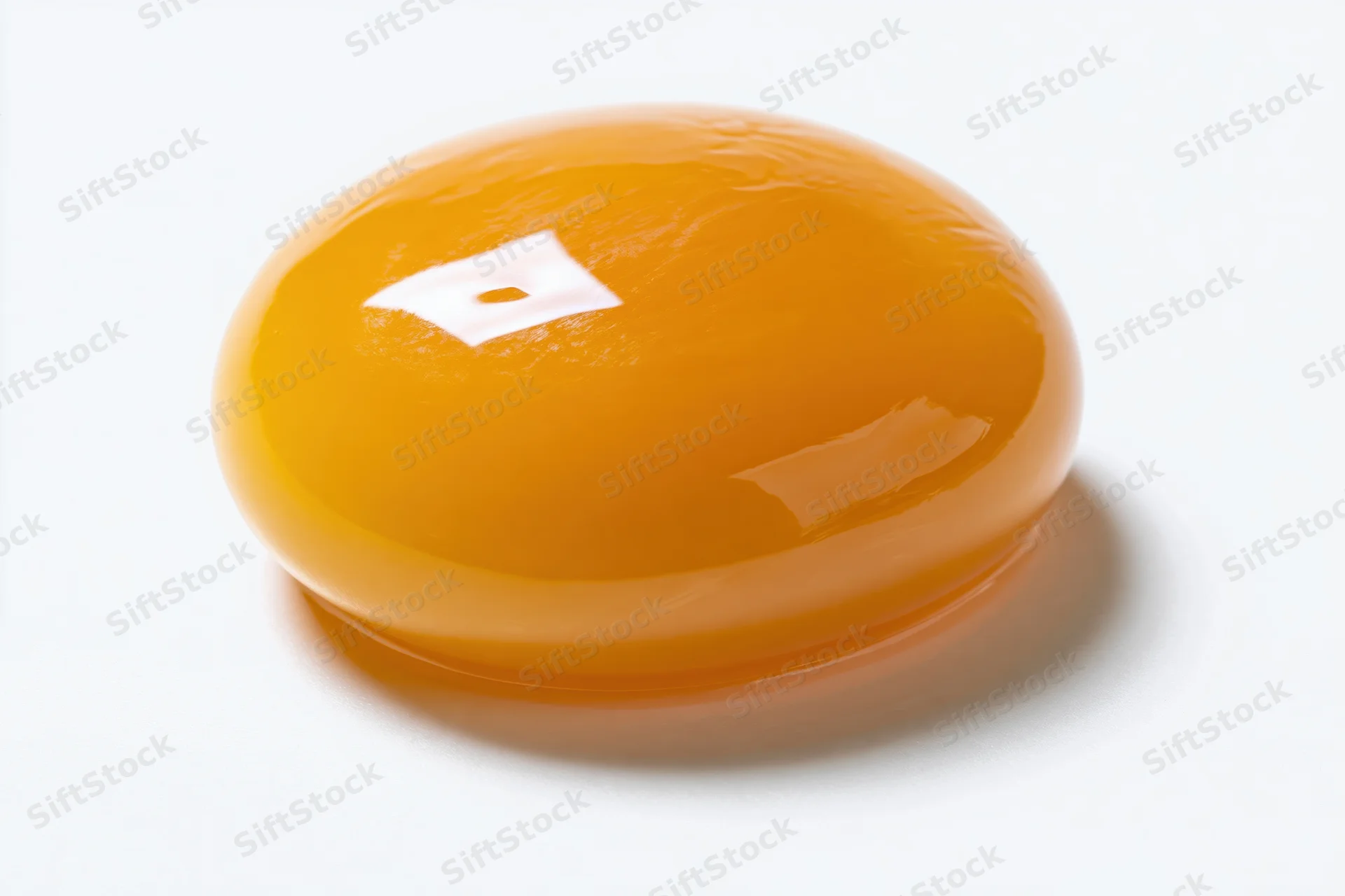 A single raw egg yolk resting intact on a pure white surface