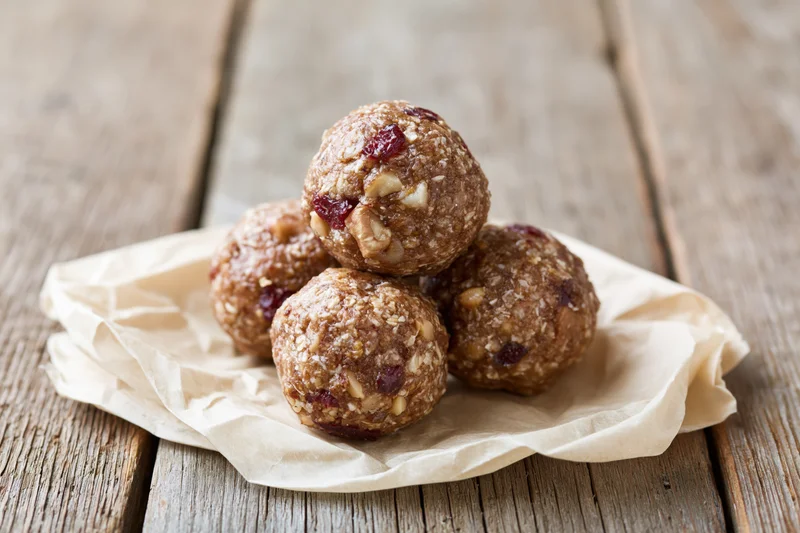 Homemade energy balls stacked in pyramid on crumpled parchment paper on wooden table
