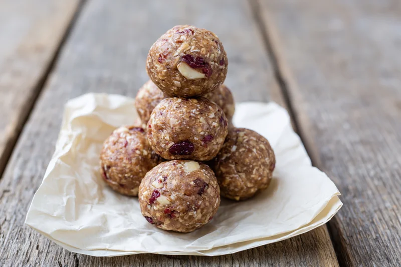 Homemade energy balls stacked in pyramid on parchment paper on wooden table