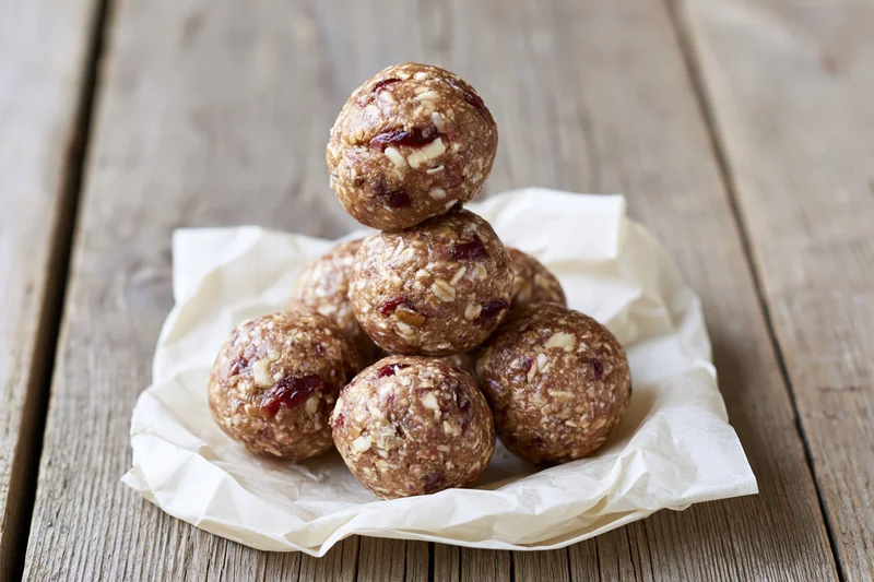 Homemade energy balls stacked in pyramid on parchment paper on wooden table