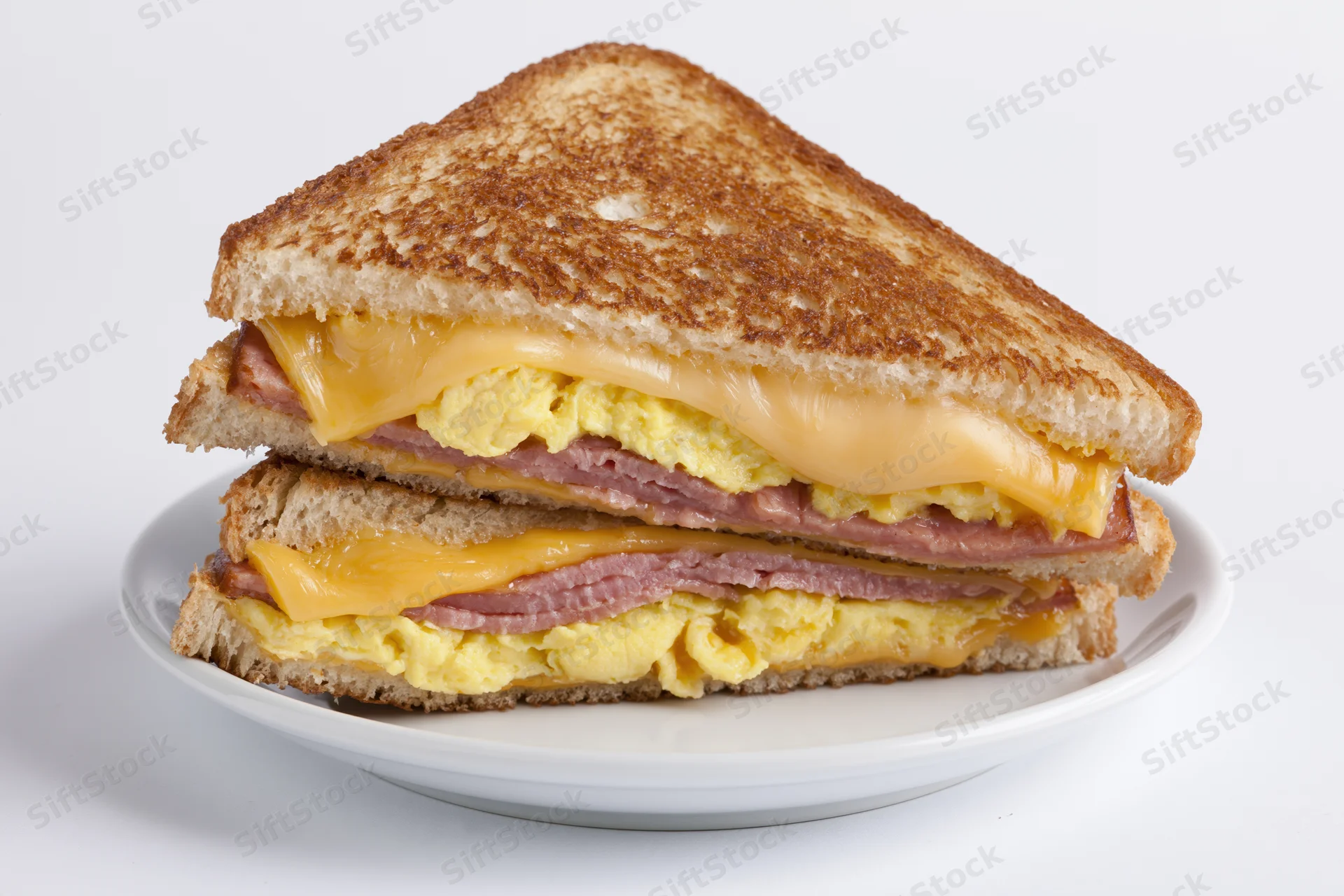 Grilled egg and cheese sandwich cut diagonally in half stacked on a white plate