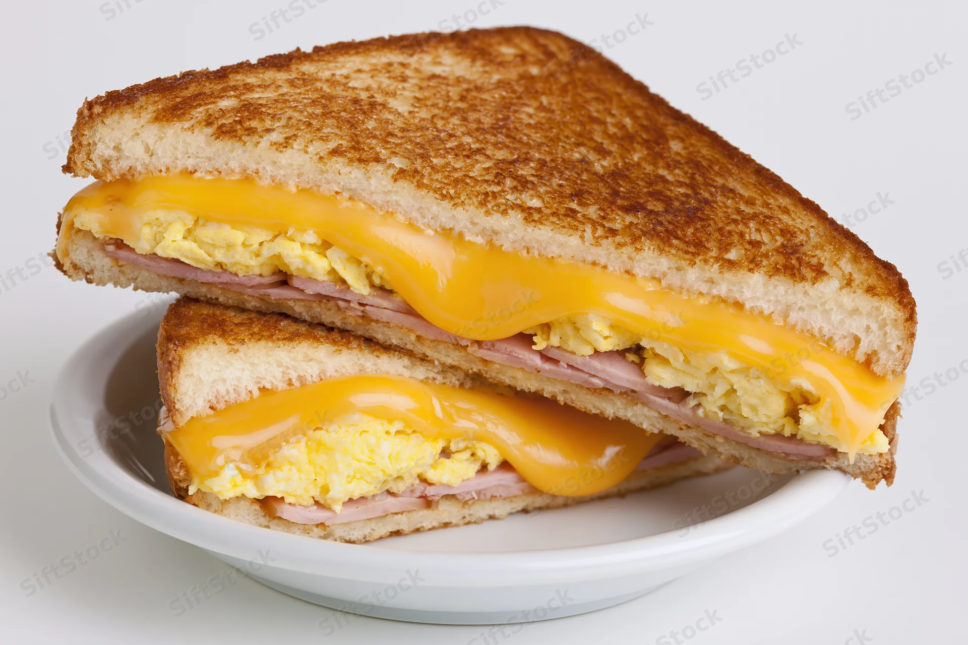 Grilled egg and cheese sandwich cut diagonally in half stacked on a white plate