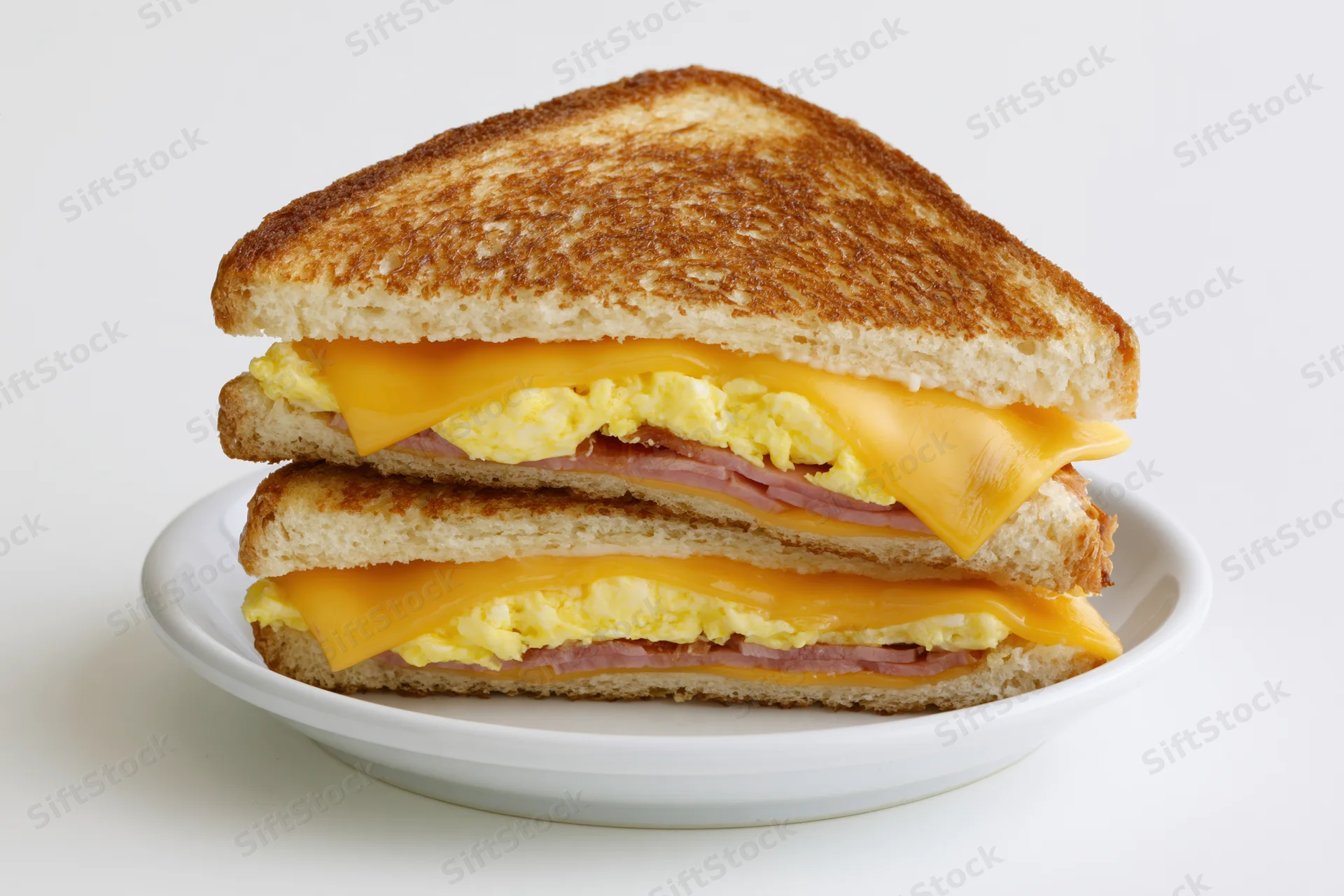Grilled egg and cheese sandwich cut diagonally in half stacked on a white plate