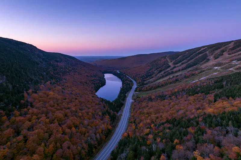 Aerial wide shot of a mountain valley in peak autumn foliage