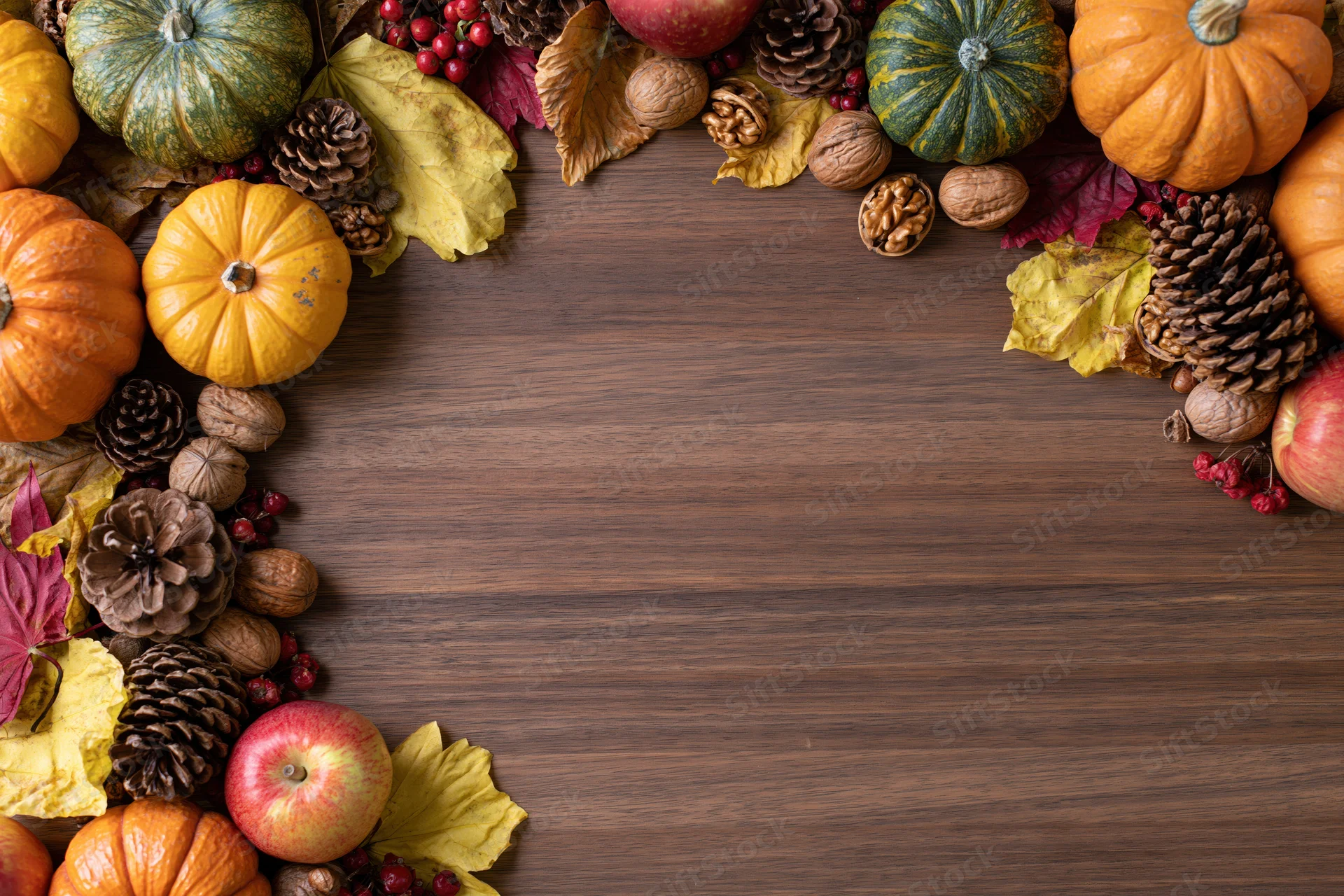 Autumn harvest arrangement framing edges of wooden table with copyspace in center