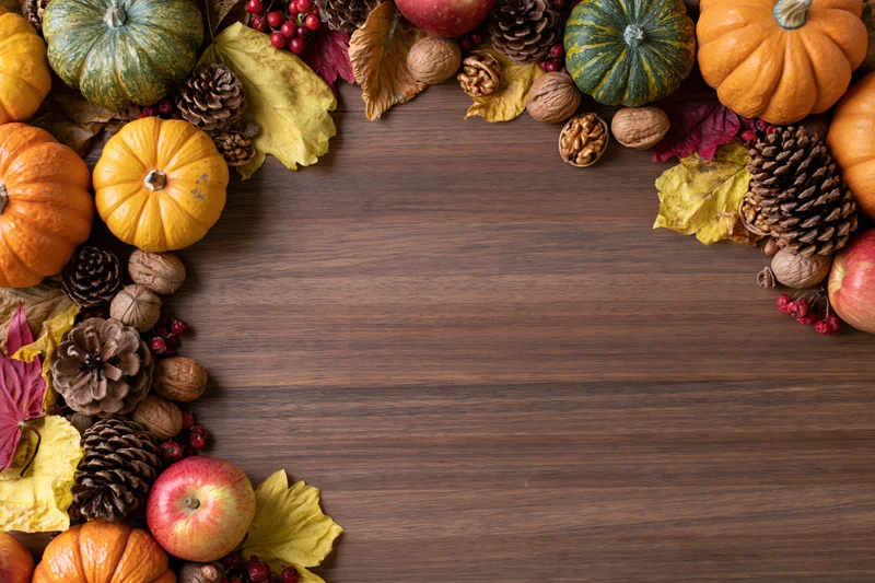 Autumn harvest arrangement framing edges of wooden table with copyspace in center