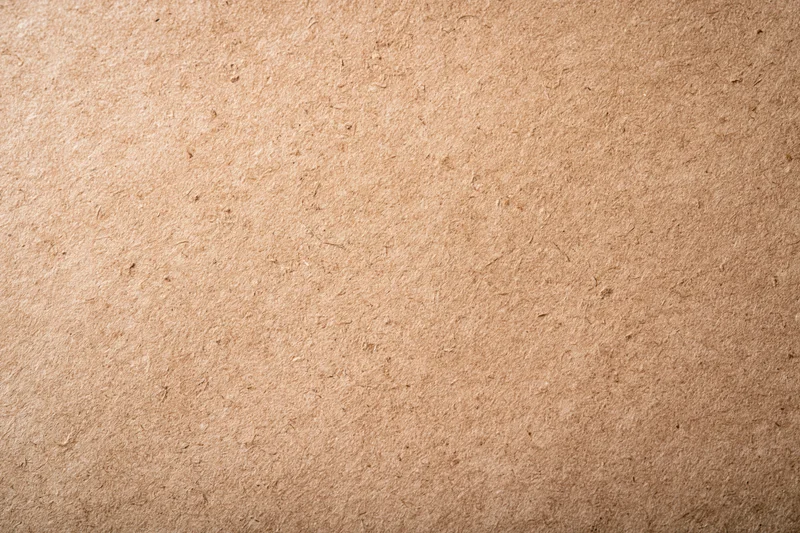 Close-up flat lay of a smooth kraft paper surface with visible texture and natural fiber grain