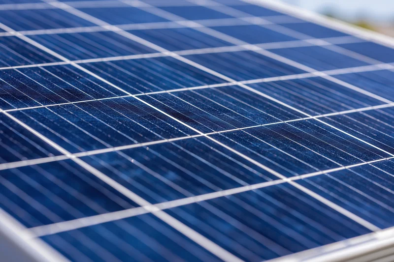 Close-up of a solar panel surface showing blue photovoltaic cells with white gridlines