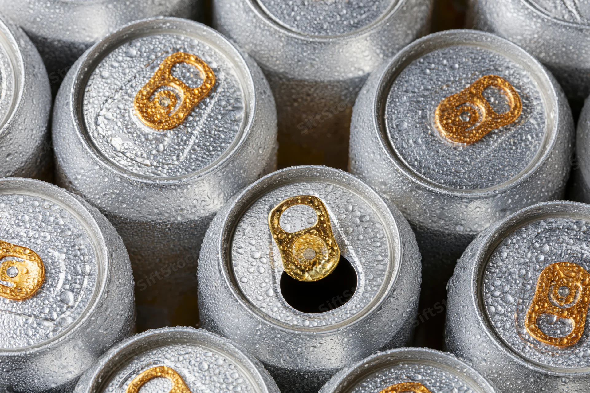 Overhead closeup of multiple chilled aluminum beverage cans with condensation, some open, arranged in a cluster