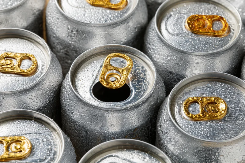 Overhead closeup of chilled aluminum beverage cans with condensation and gold pulltabs clustered together