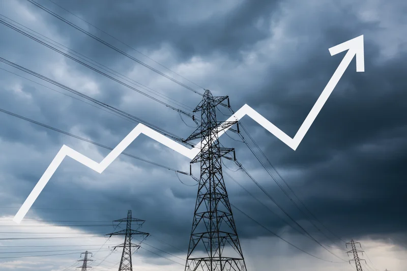 High-voltage electricity transmission towers under stormy sky with upward trending graph overlay