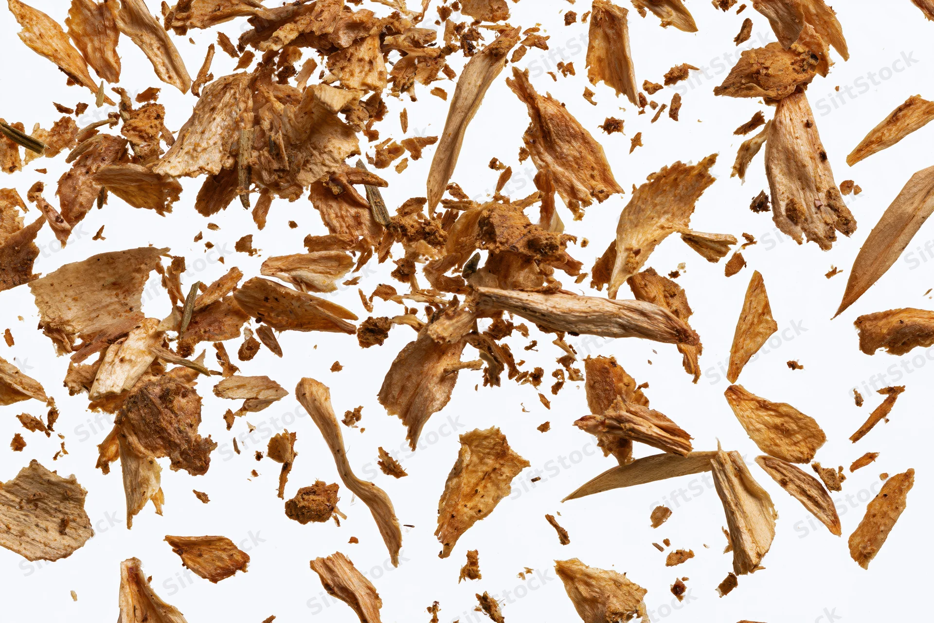 Dried herb and spice flakes scattered and suspended against a white background