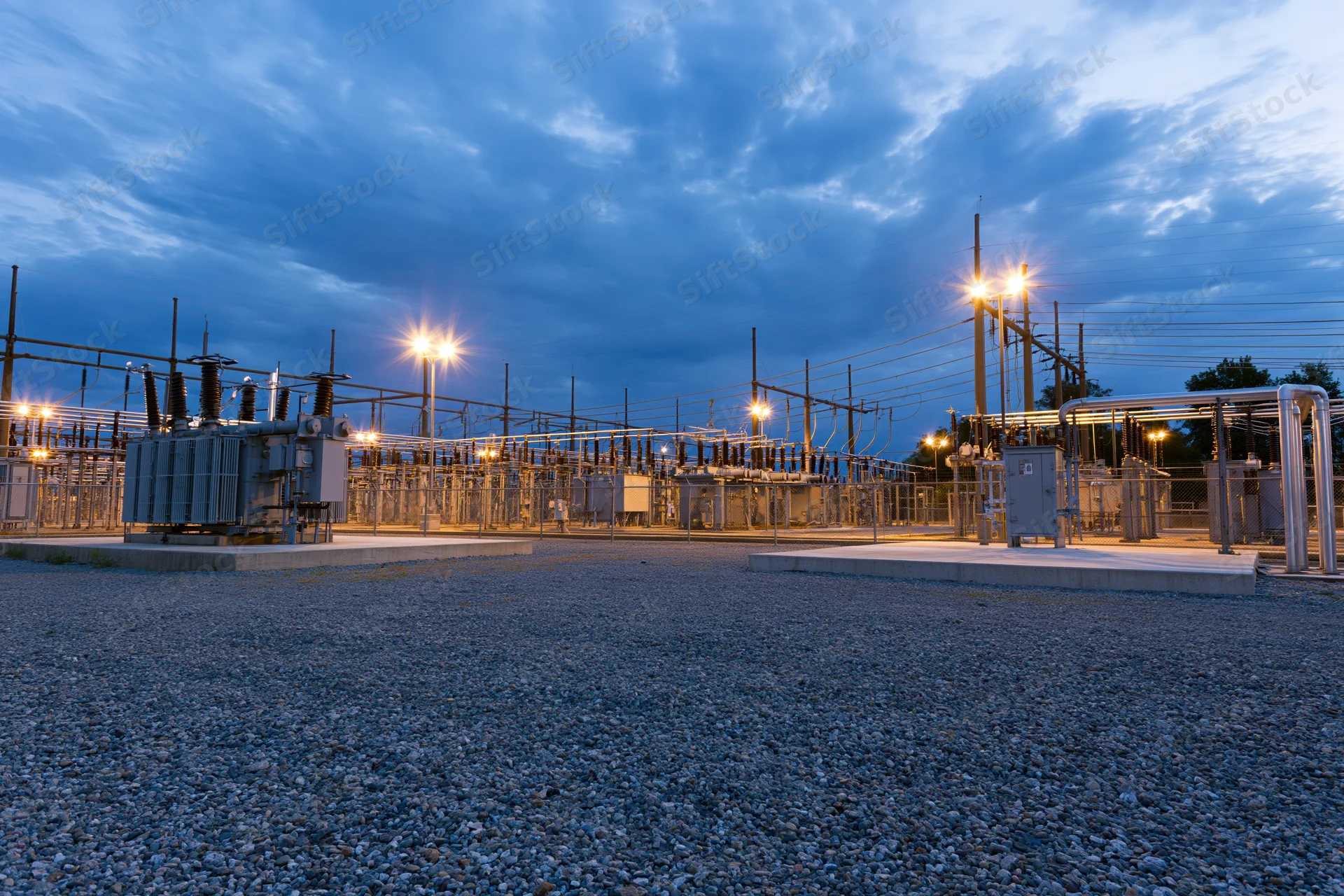 Electrical substation with rows of high-voltage transformers under twilight sky