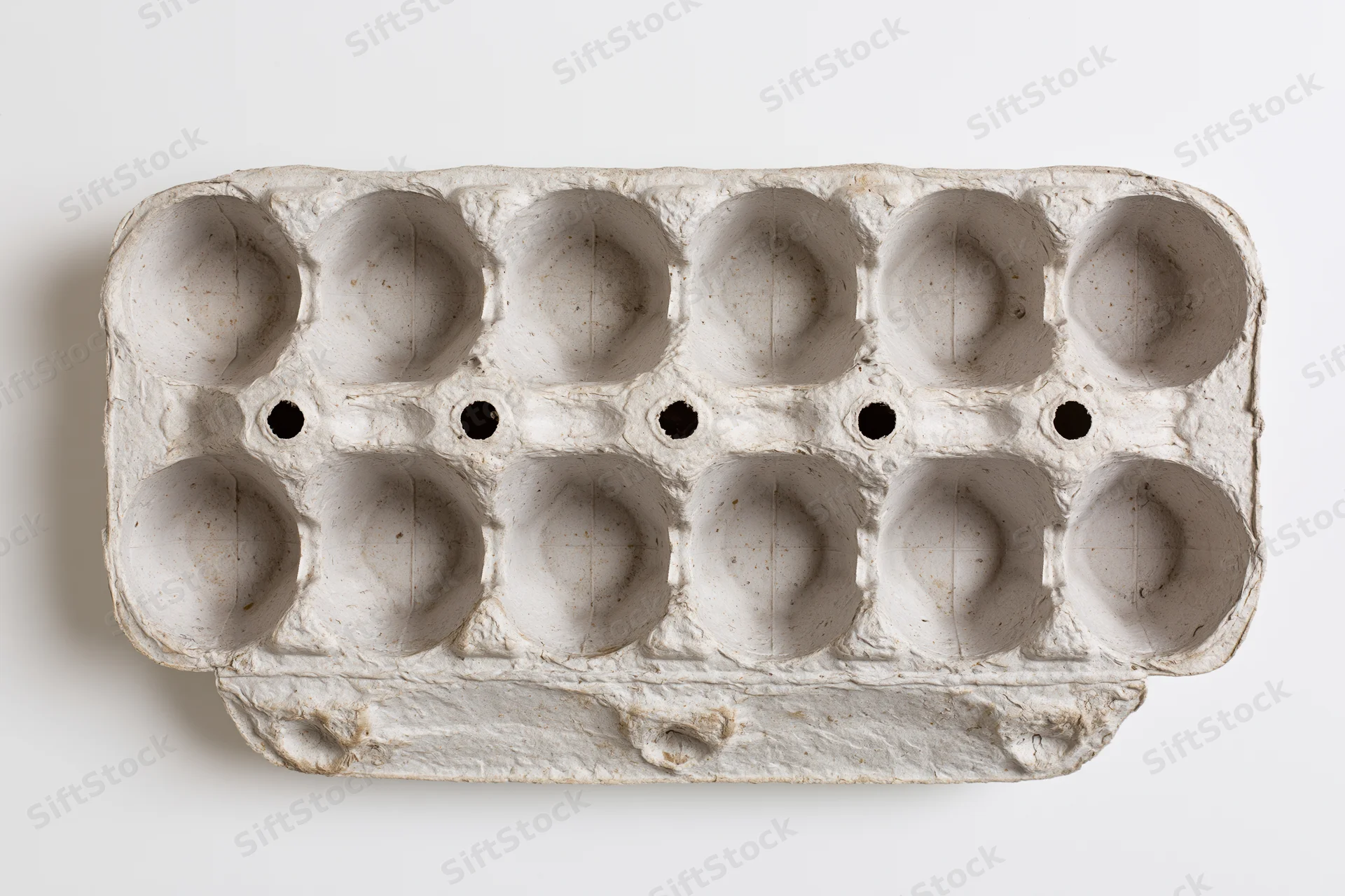 Empty twelve-cup recycled cardboard egg carton lying open on white surface