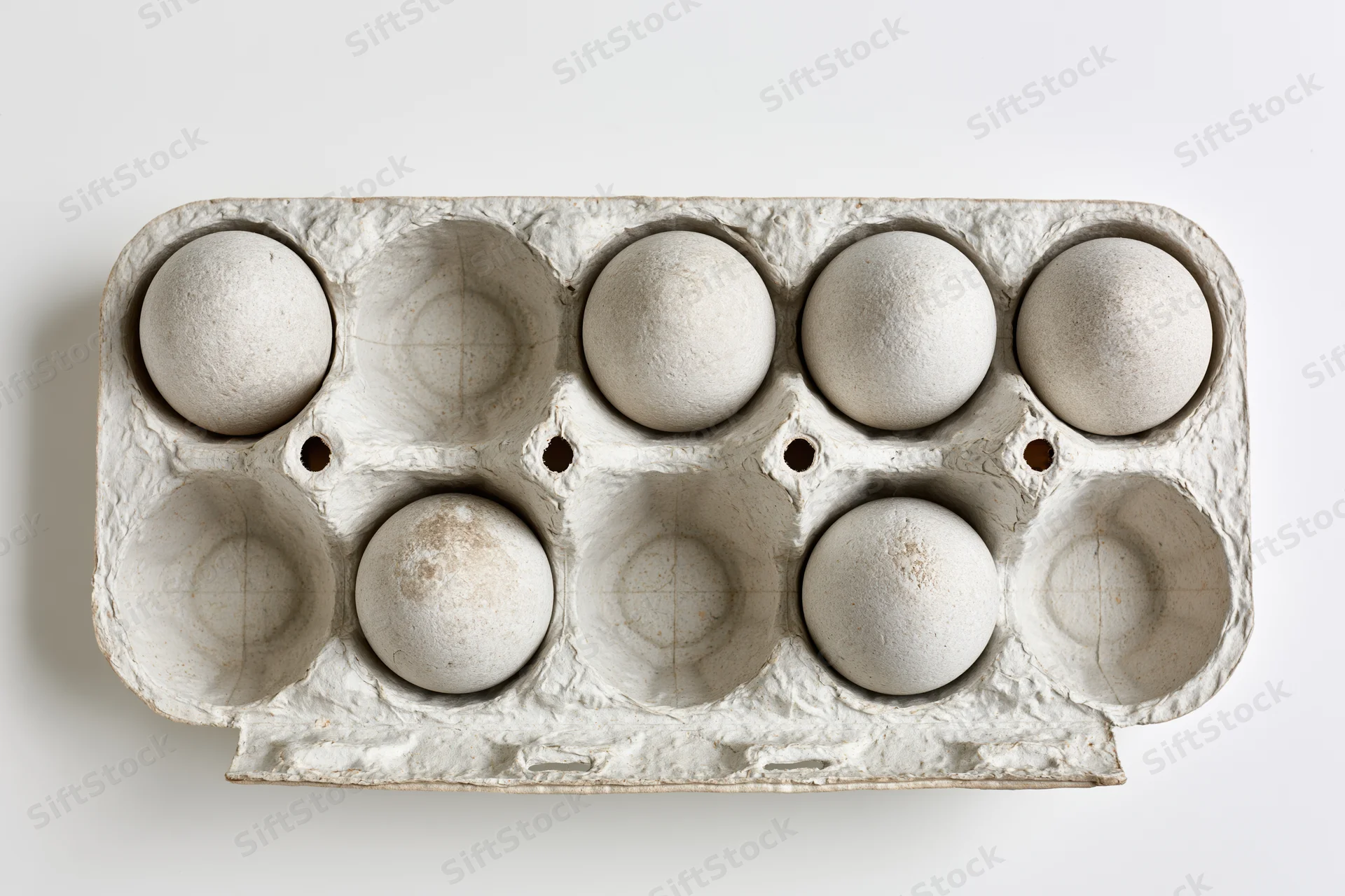 Open recycled cardboard egg carton with six white eggs arranged in two rows on plain white background