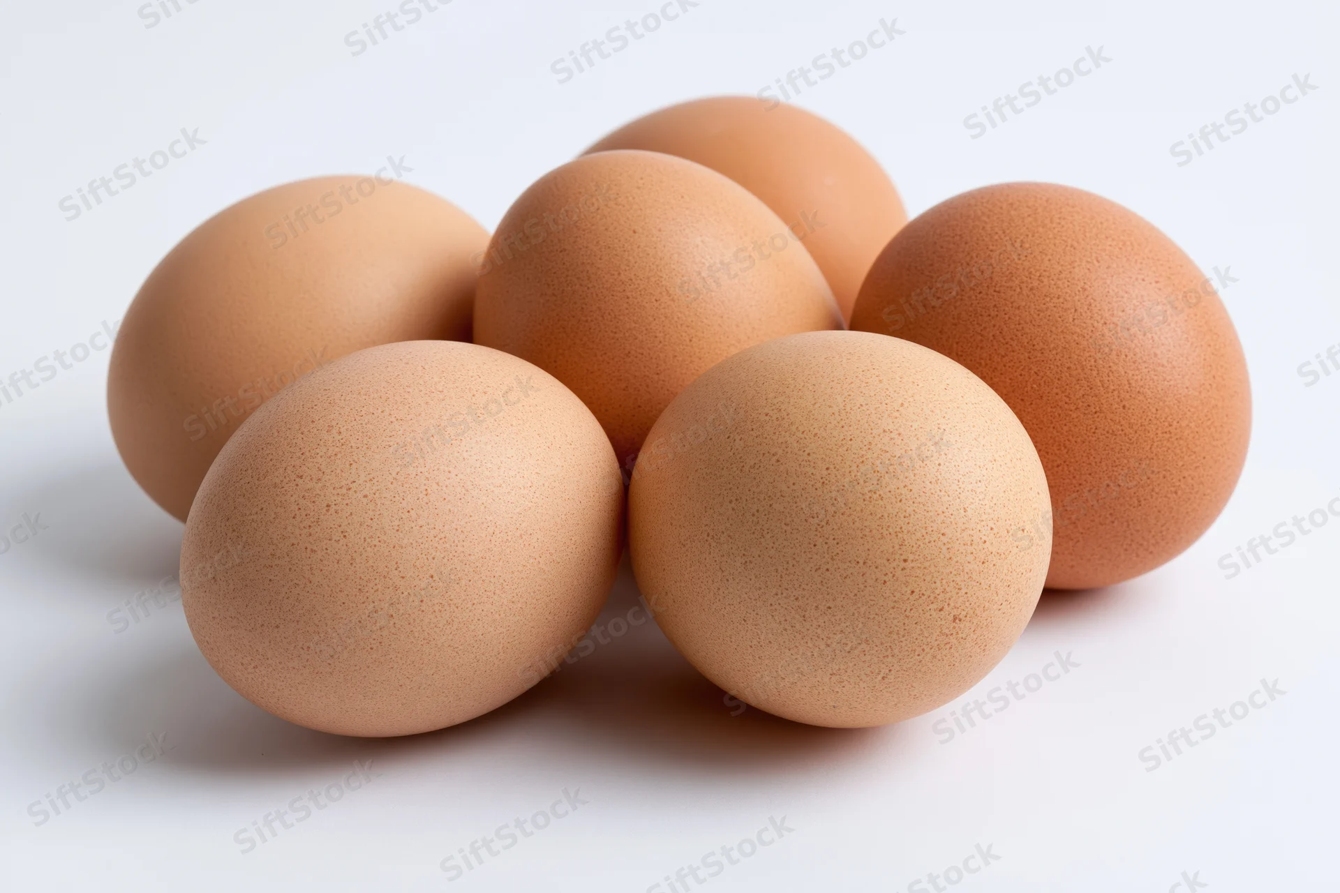 Brown chicken eggs grouped together on a white surface