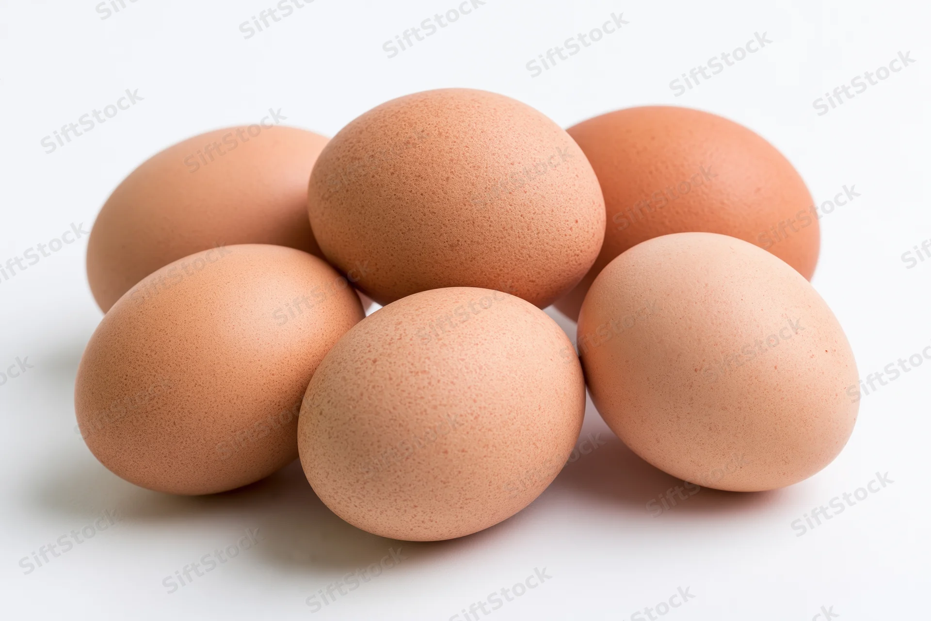 Brown chicken eggs grouped in a loose cluster on a white surface