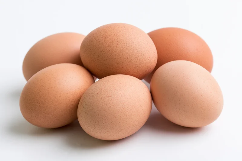Brown chicken eggs grouped in a loose cluster on a white surface