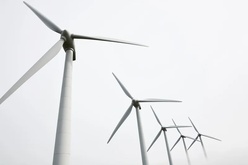 Wind turbines aligned in diagonal perspective receding into overcast sky