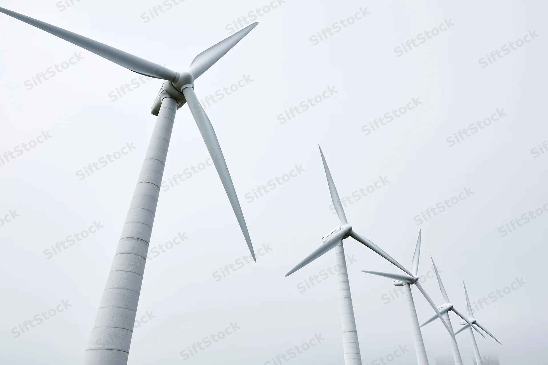 Wind turbines arranged in diagonal row receding into overcast sky