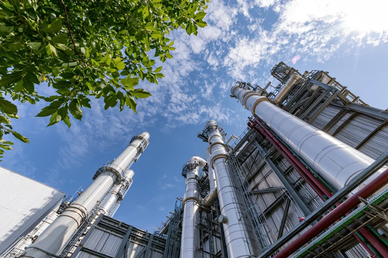 Industrial gas turbine power plant viewed from low angle with sky and tree foliage above