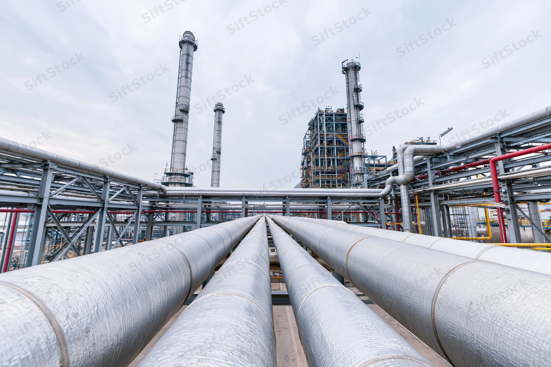 Insulated steel pipelines running through an industrial plant with tall towers and metal frameworks