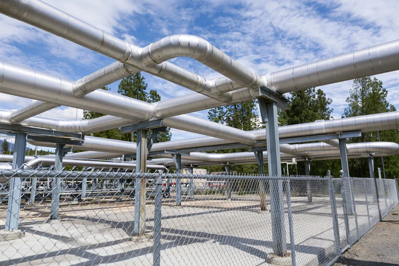 Insulated metal pipelines forming a network supported by steel columns within a fenced geothermal facility