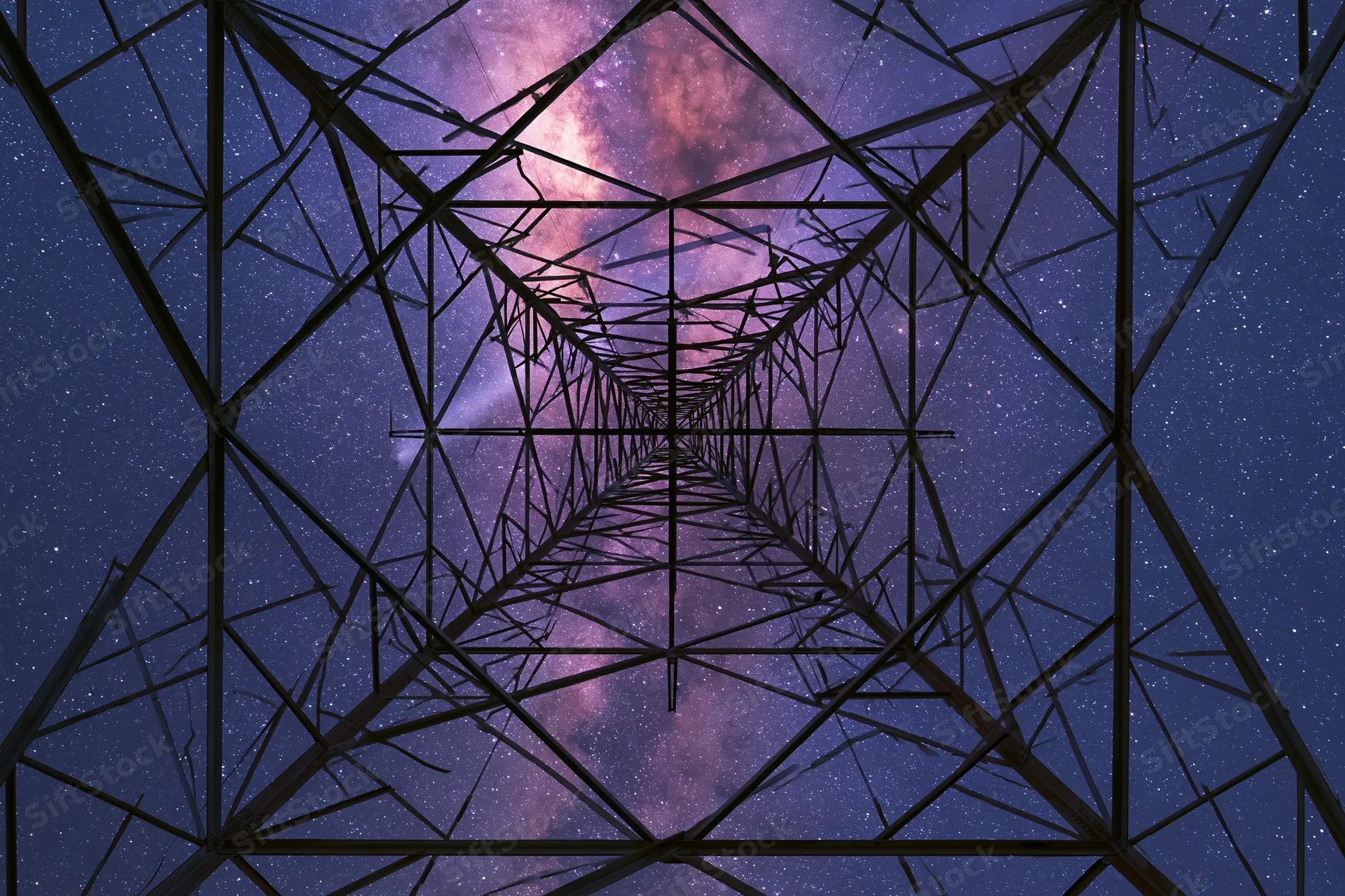 Steel electricity transmission tower viewed from base looking up at starry night sky with milky way visible through lattice structure