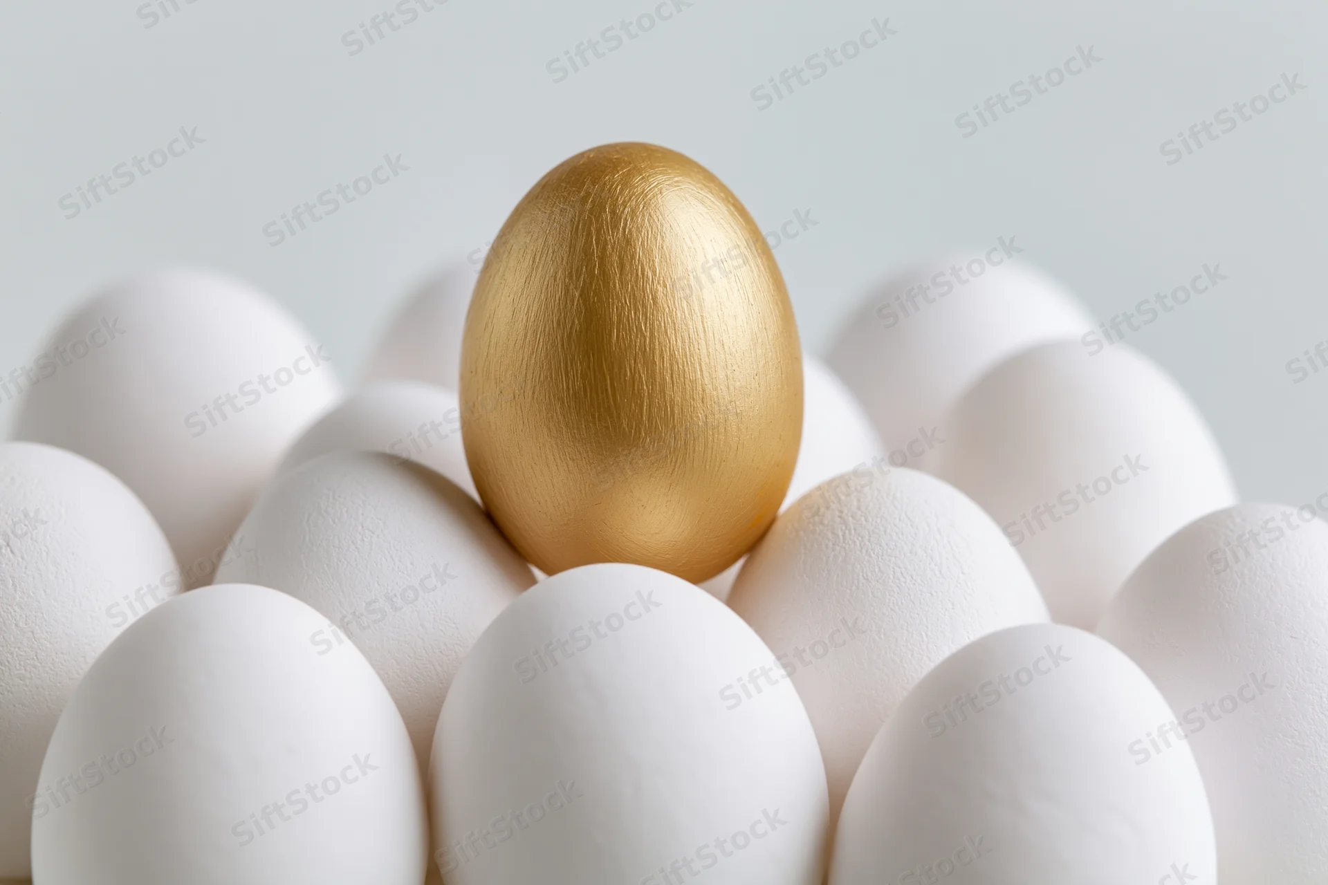 Golden egg standing among white eggs in a cluster