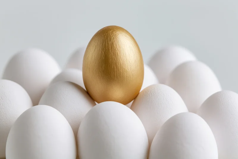 Golden egg standing among white eggs in a cluster