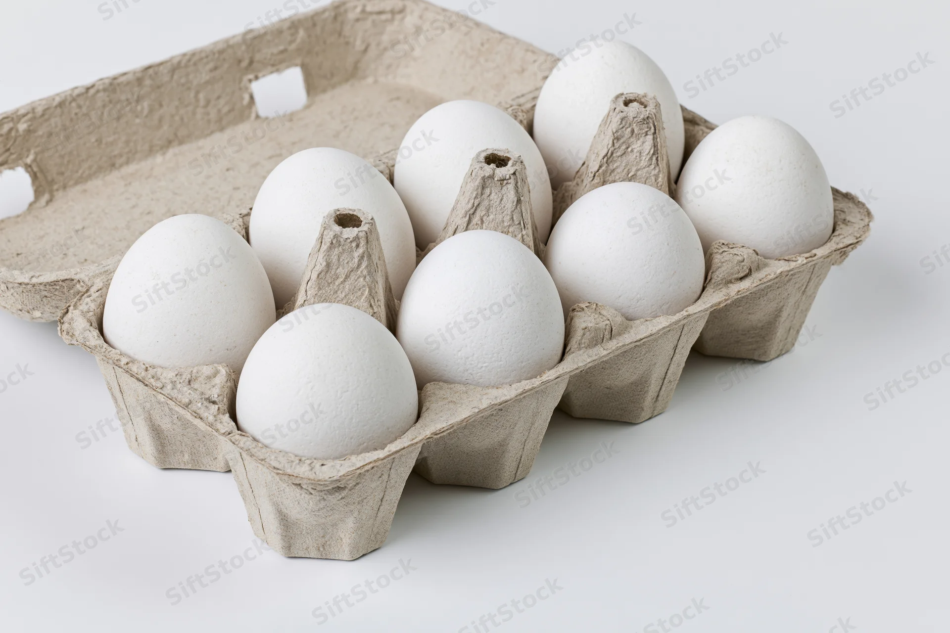 Open cardboard egg carton holding ten white eggs viewed from above on white background