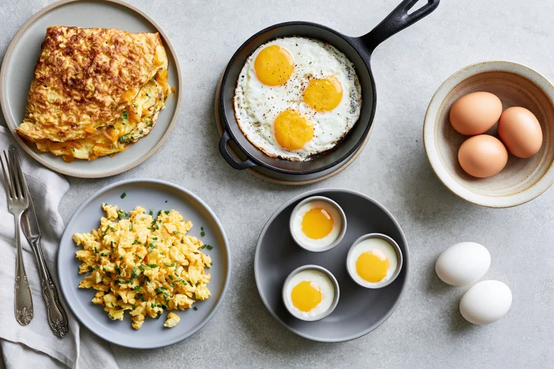 Various egg dishes arranged in a flat lay on a light gray surface