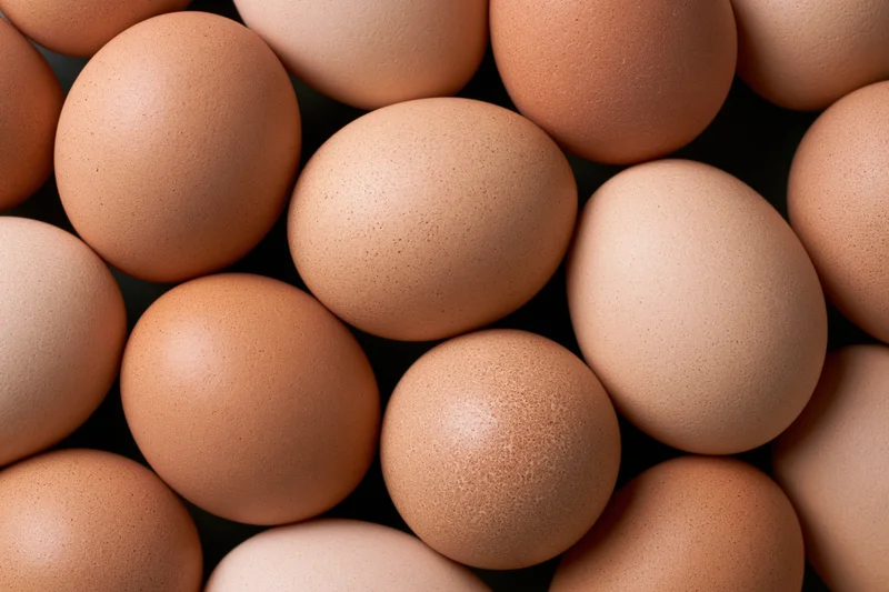 Brown chicken eggs arranged in a dense top-down pile filling the frame