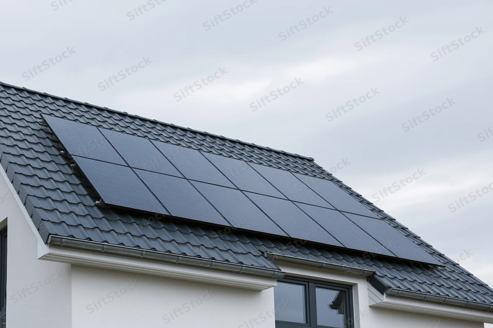 Solar panels installed on a residential house rooftop under an overcast sky