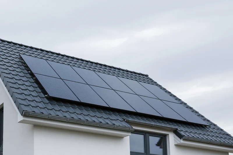 Solar panels installed on a residential house rooftop under an overcast sky