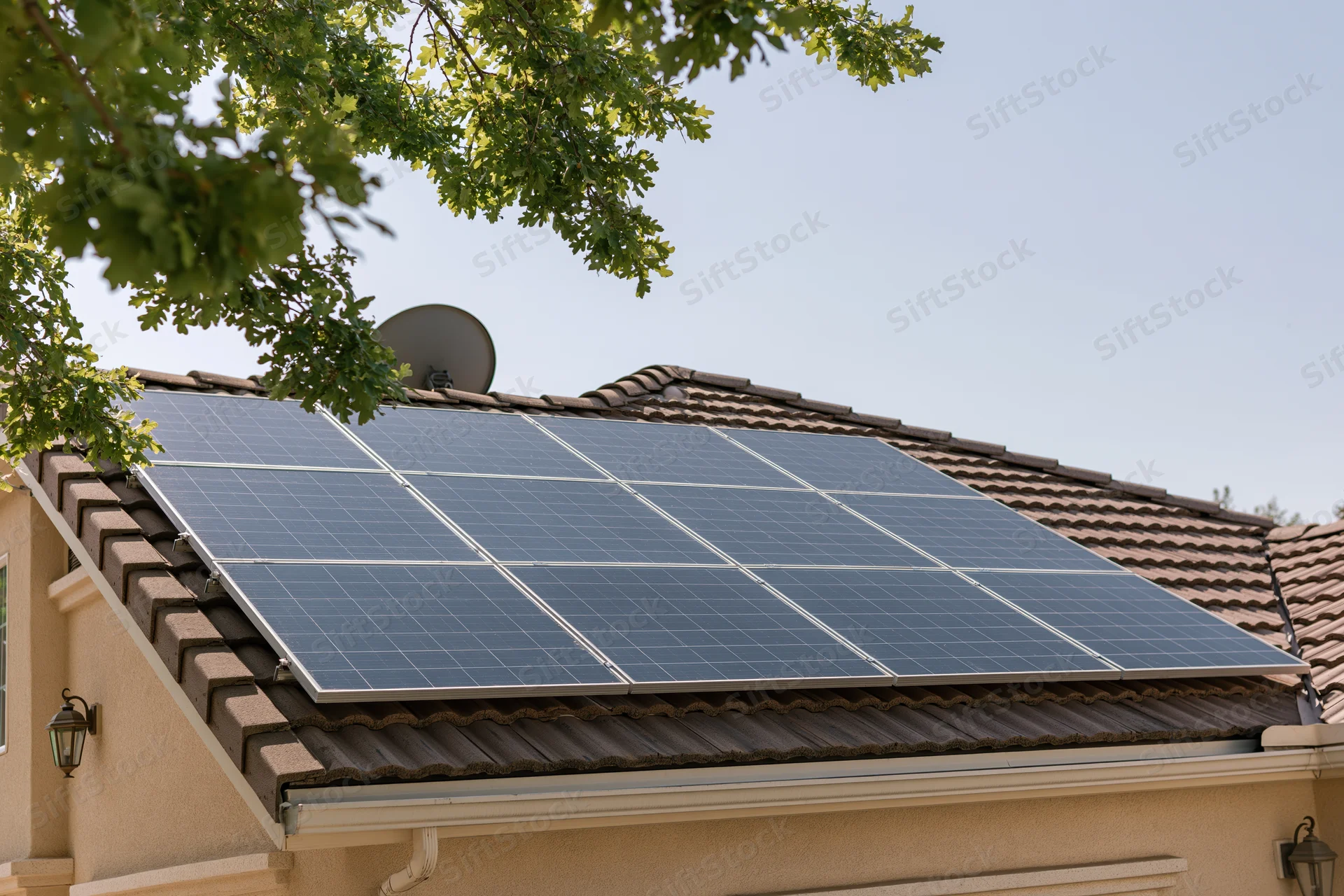 Solar panels installed on a residential rooftop with brown shingles and a satellite dish nearby