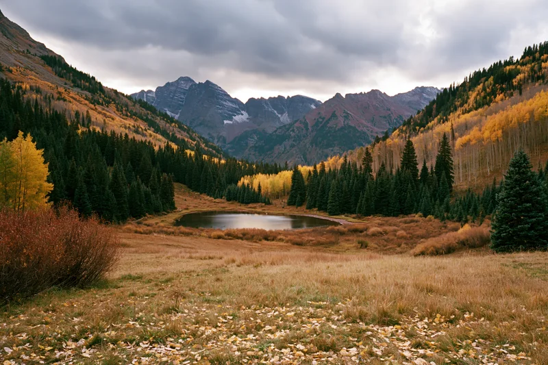 Alpine lake surrounded by autumn-colored trees and mountains in a valley