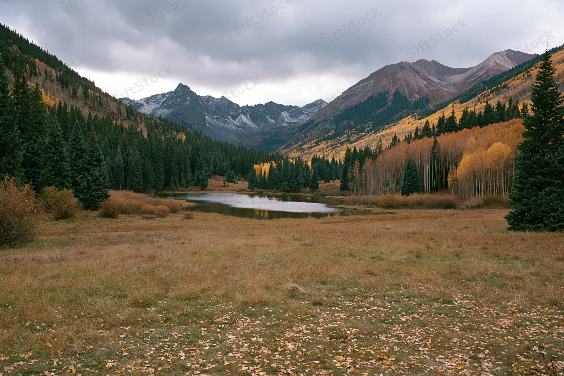 Alpine lake surrounded by autumn-colored aspen and pine trees in a mountain valley