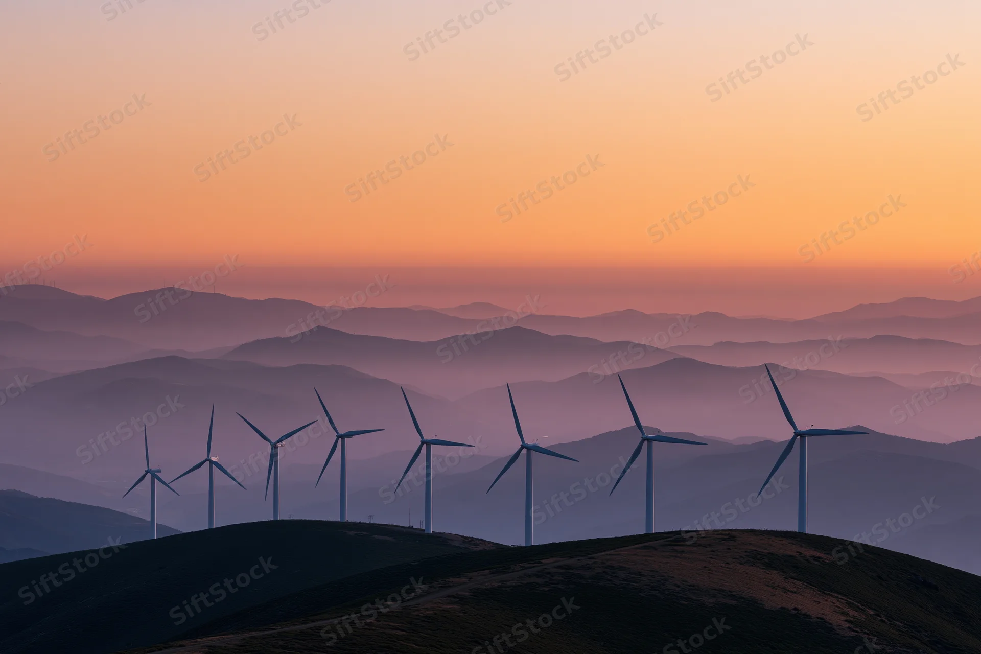 Row of wind turbines silhouetted on a mountain ridgeline at sunset