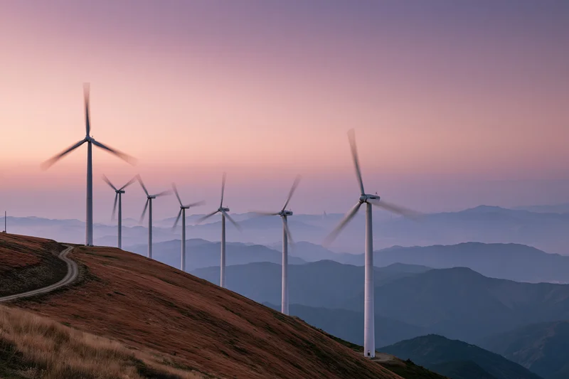 Row of wind turbines along a mountain ridge at dusk