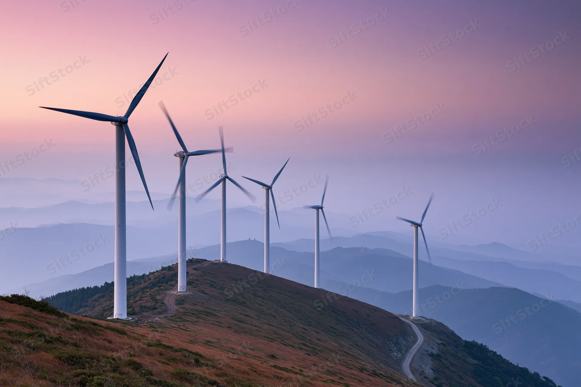Row of wind turbines along a mountain ridge at dusk
