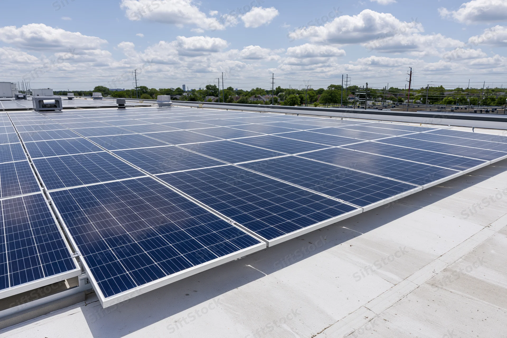 Rows of solar panels installed on a flat commercial rooftop under a partly cloudy sky
