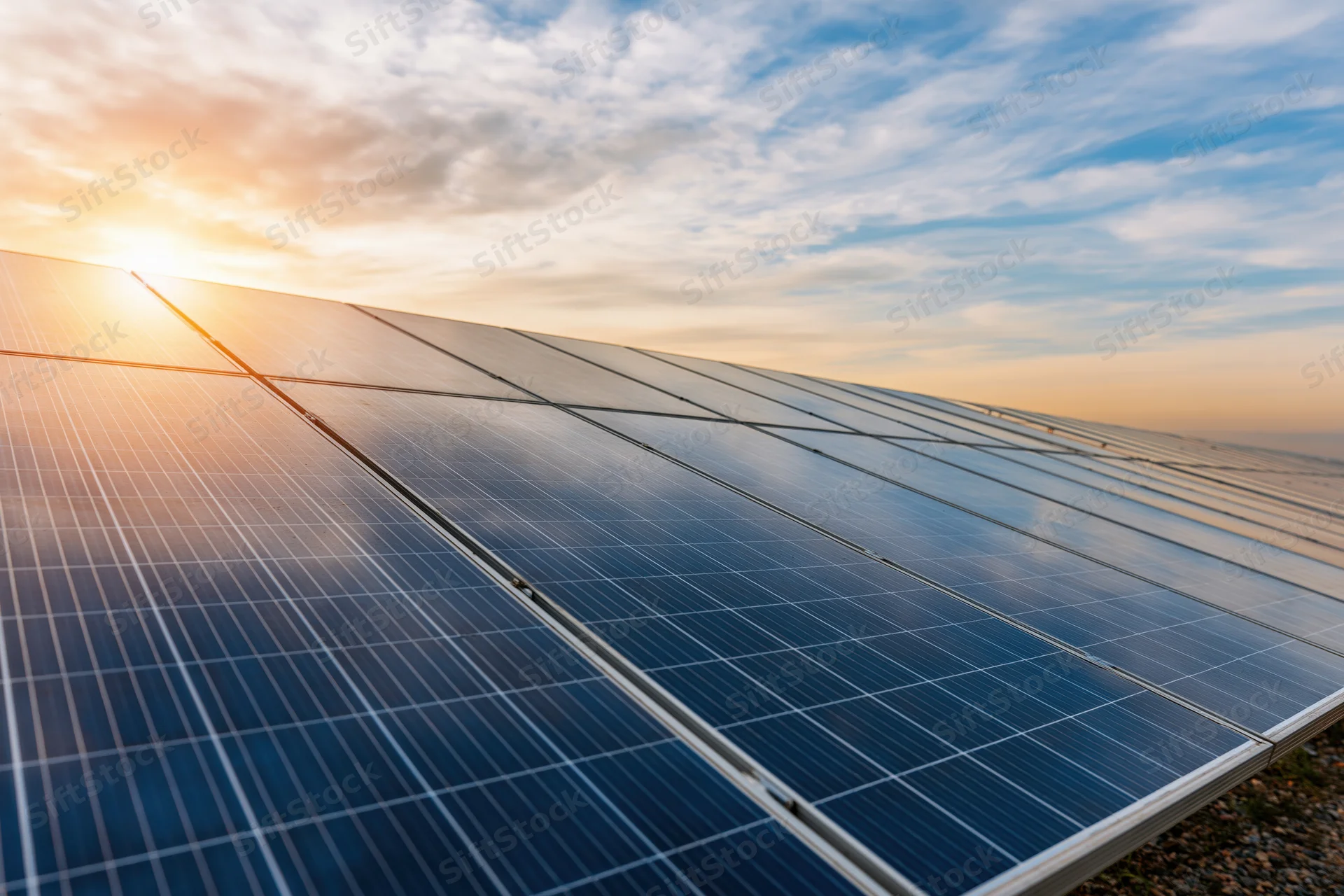 Rows of solar panels stretching to the horizon under a sunset sky